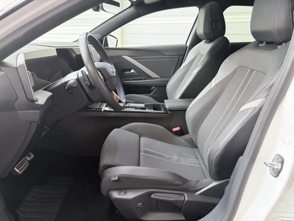 Vue intérieure côté conducteur de l'Opel Astra blanche, avec sièges GS en cuir synthétique et volant multifonctions.