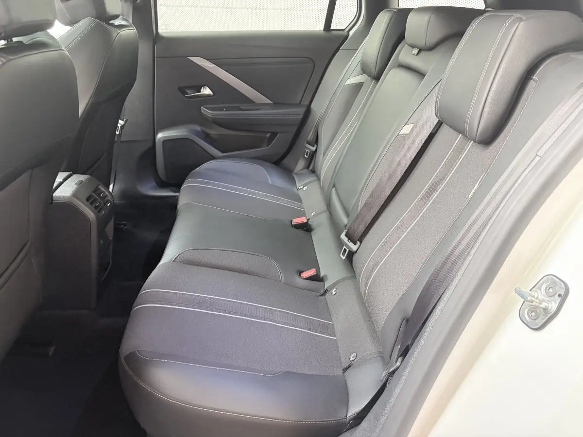Vue intérieure côté droit sur la banquette arrière noire de l’Opel Astra blanche avec porte ouverte.