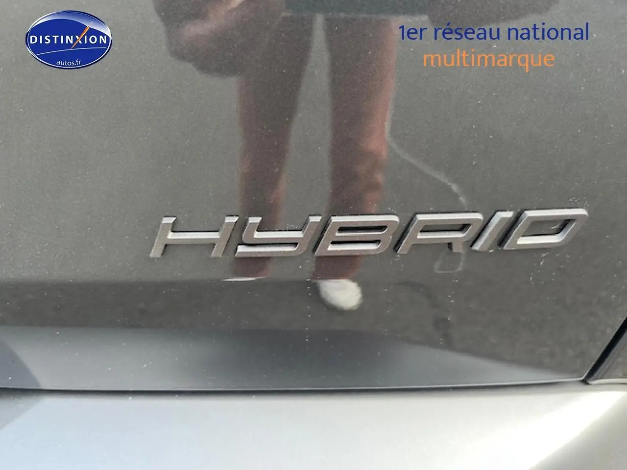 Gros plan sur l’inscription "Hybrid" en chrome sur la carrosserie gris titane d’un Peugeot 3008.