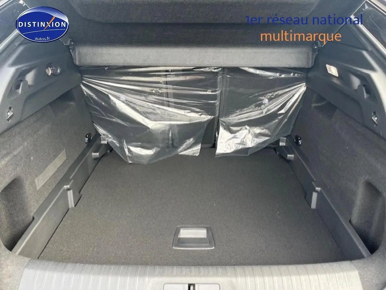Vue intérieure du coffre spacieux du Peugeot 3008 gris titane, avec banquette arrière protégée par plastique transparent.