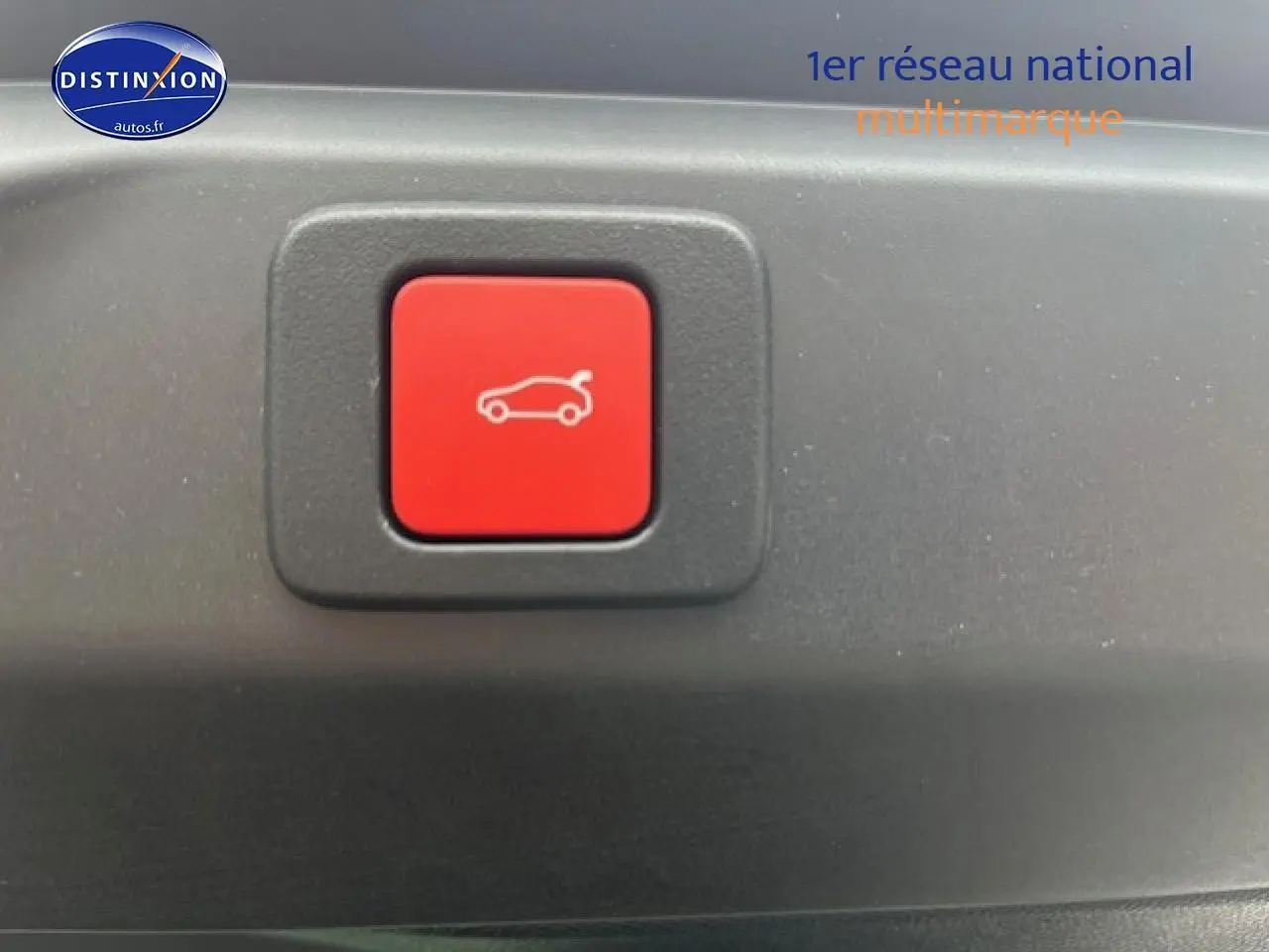 Bouton rouge d'ouverture électrique du coffre sur un Peugeot 3008 gris titane, vue rapprochée intérieure.