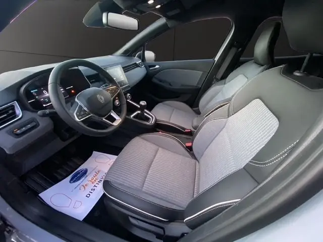 Intérieur avant droit de la Renault Clio gris clair 2025, volant cuir, écran tactile central et sièges tissu bi-ton.