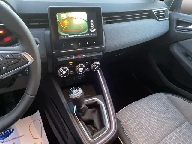 Vue intérieure côté conducteur de la Renault Clio Techno TCe 90 2025, avec écran tactile central et levier de vitesses manuel.