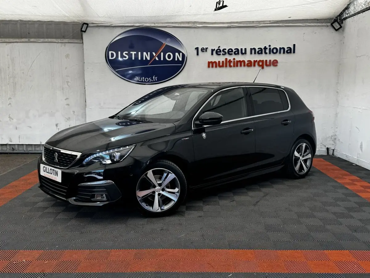 Peugeot 308 noir vue 3/4 avant droit dans un showroom avec jantes alliage et phares LED allumés.