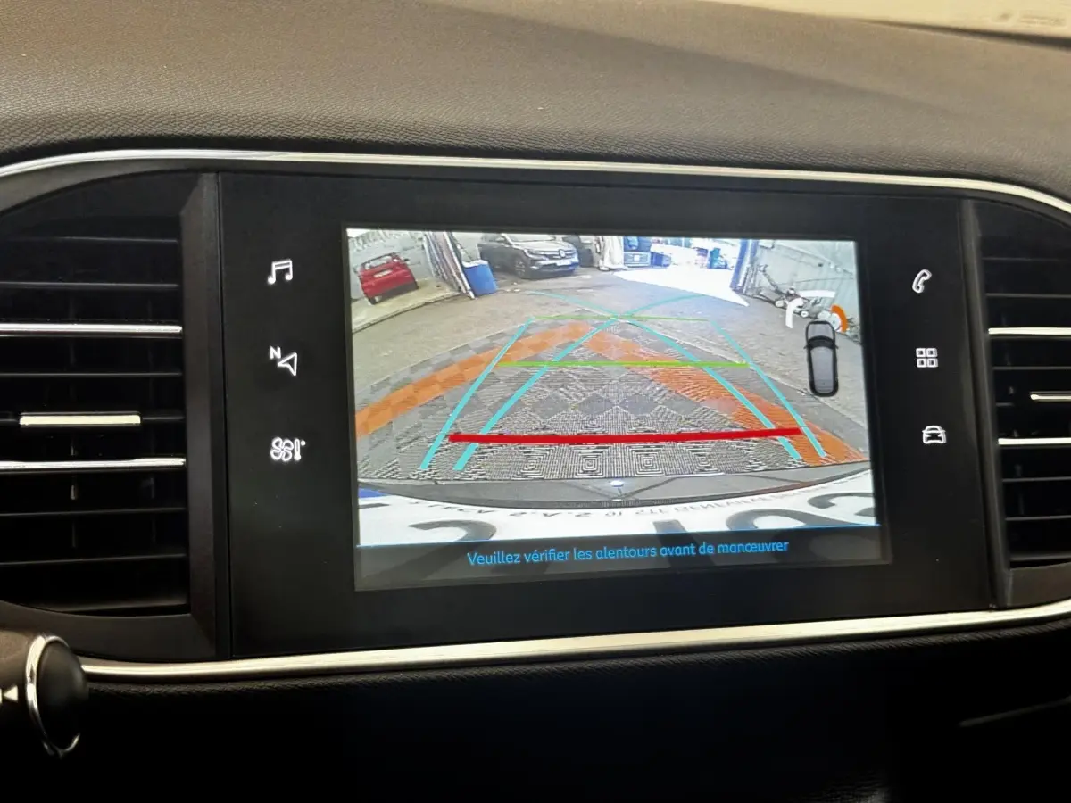 Écran tactile intérieur montrant la caméra de recul avec guidage de trajectoire sur Peugeot 308 noire.