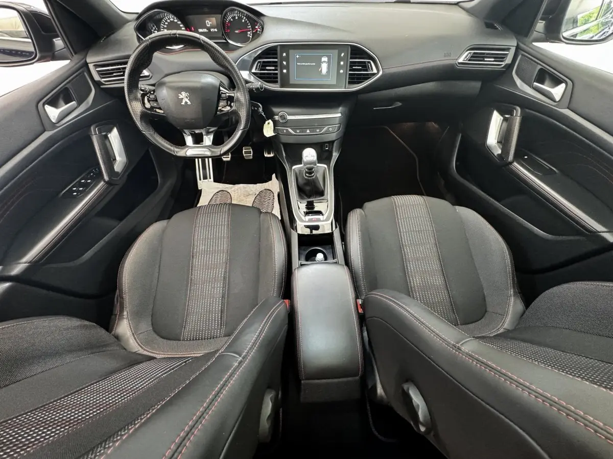 Vue intérieure avant de la Peugeot 308 GT Line 2018, montrant le volant cuir, la console centrale avec boîte manuelle et l’écran tactile.