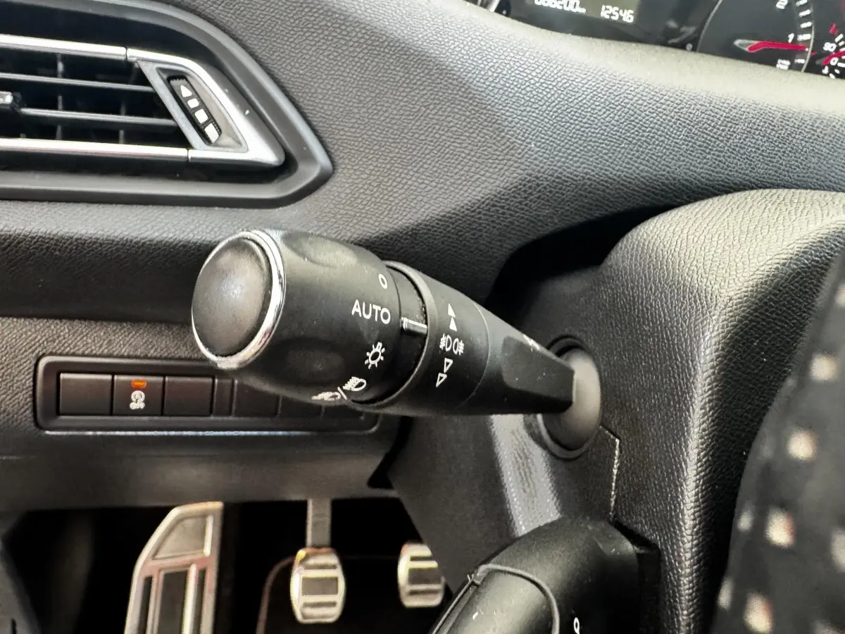Gros plan sur la manette de commande des phares à gauche du volant dans l’habitacle noir du Peugeot 308 GT Line 2018.