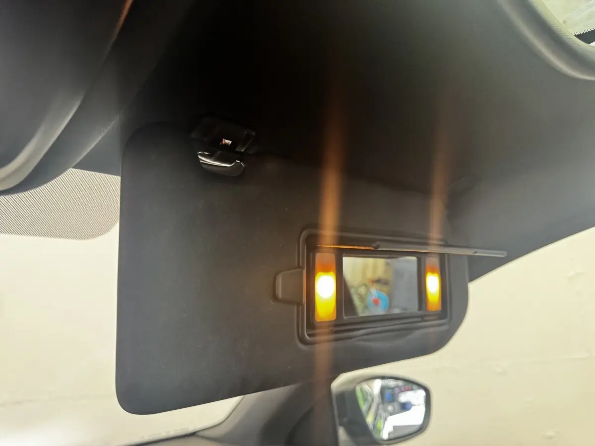 Détail intérieur du pare-soleil avec miroir éclairé sur la Peugeot 308 noire, vue côté conducteur.