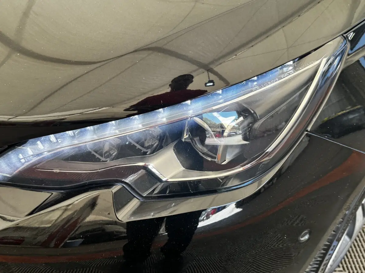 Gros plan sur le phare avant droit noir brillant de la Peugeot 308 1.5 BlueHDi 130 S&S GT Line 2018.