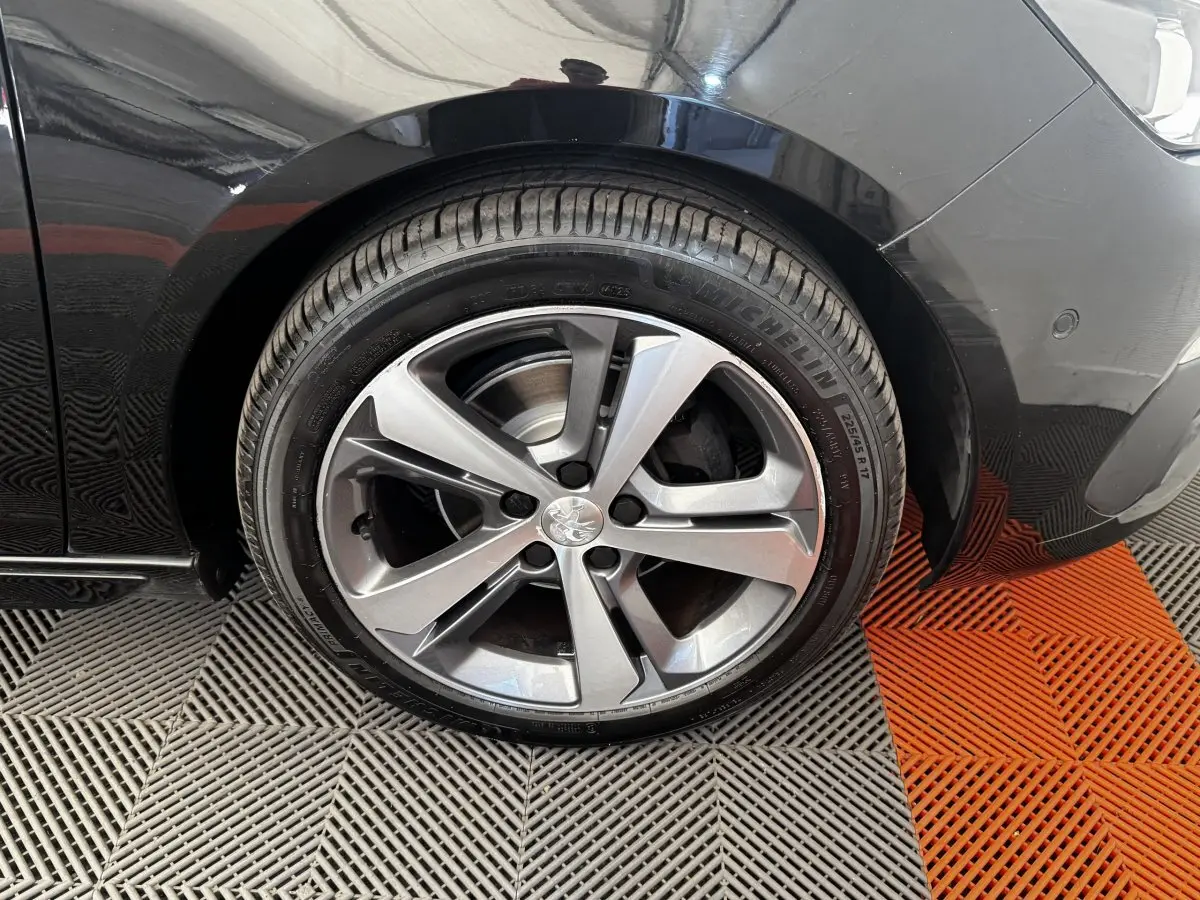 Gros plan sur la roue avant droite de la Peugeot 308 noire, avec jante alliage cinq branches et pneu Michelin.