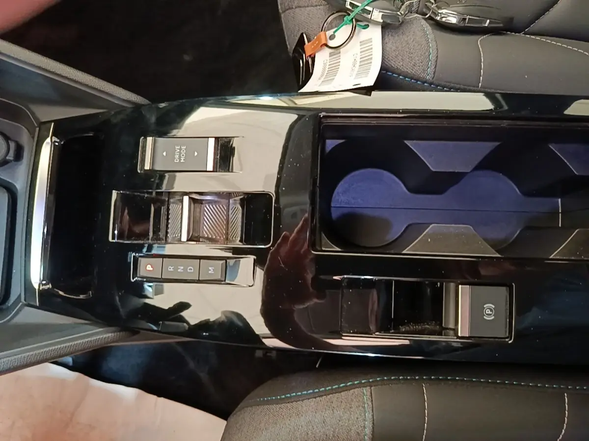 Gros plan sur la console centrale noire brillante du Citroën C4 X avec commandes de boîte auto et porte-gobelets.