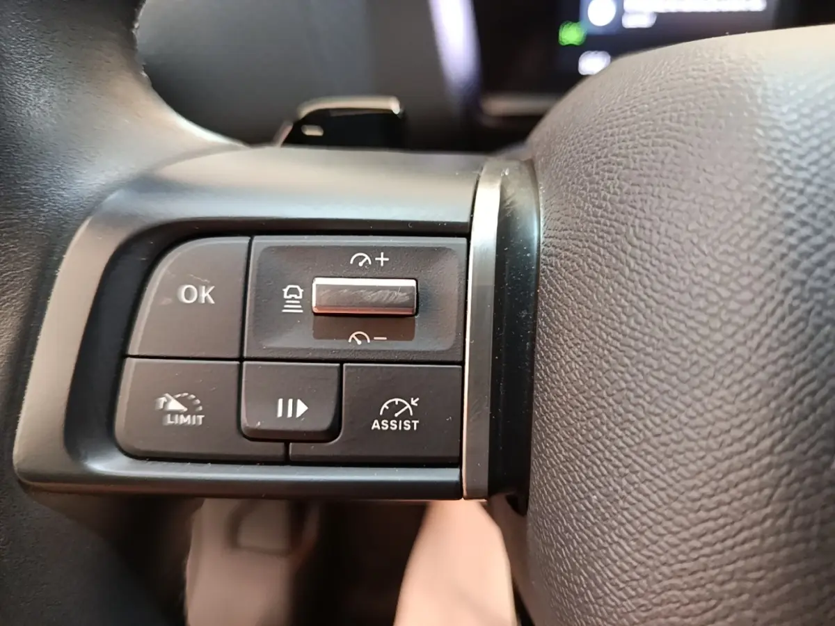 Gros plan sur les commandes multifonctions du volant cuir noir d'une Citroën C4 X PureTech 130 Shine 2023.