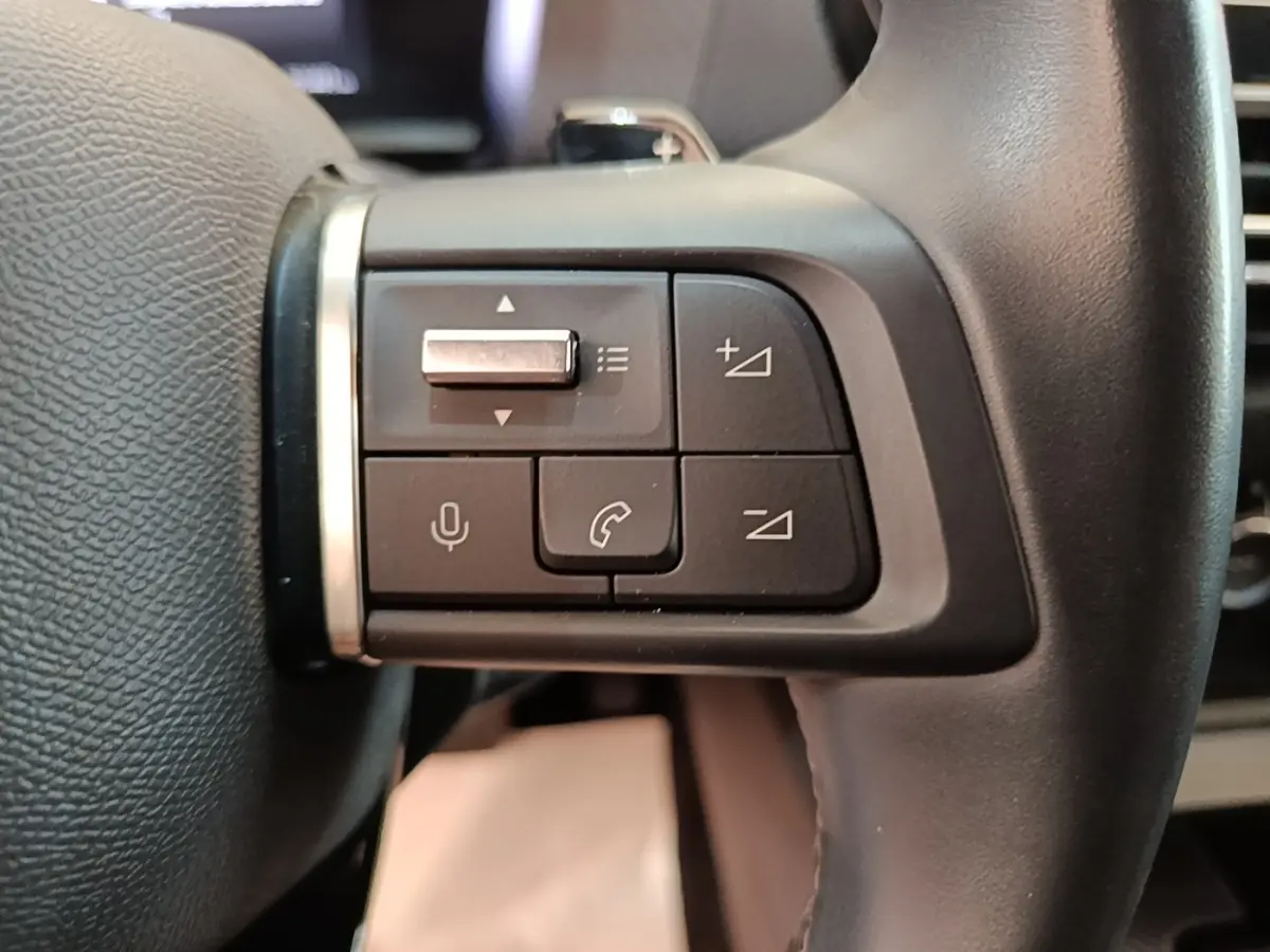 Gros plan sur les commandes gauche du volant cuir noir du Citroën C4 X 2023, boutons multifonctions et micro intégrés.