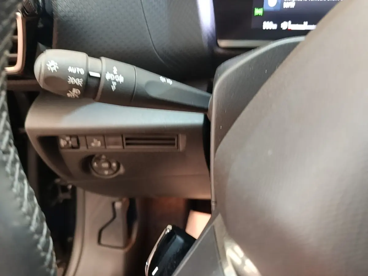 Gros plan sur la commande des phares à gauche du volant cuir noir du Citroën C4 X PureTech 130 Shine 2023.