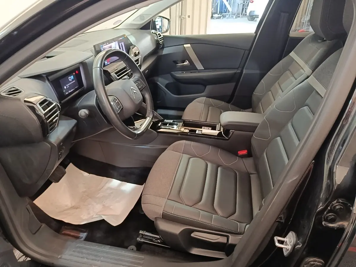 Intérieur avant droit du Citroën C4 X noir 2023 avec sièges tissu et tableau de bord digital tactile.