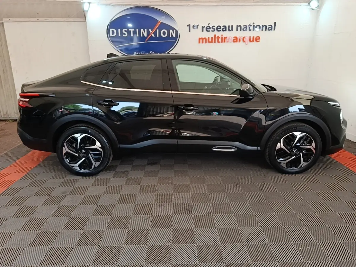 Vue de profil côté gauche d'une Citroën C4 X noire 2023 avec jantes alliage et lignes épurées.