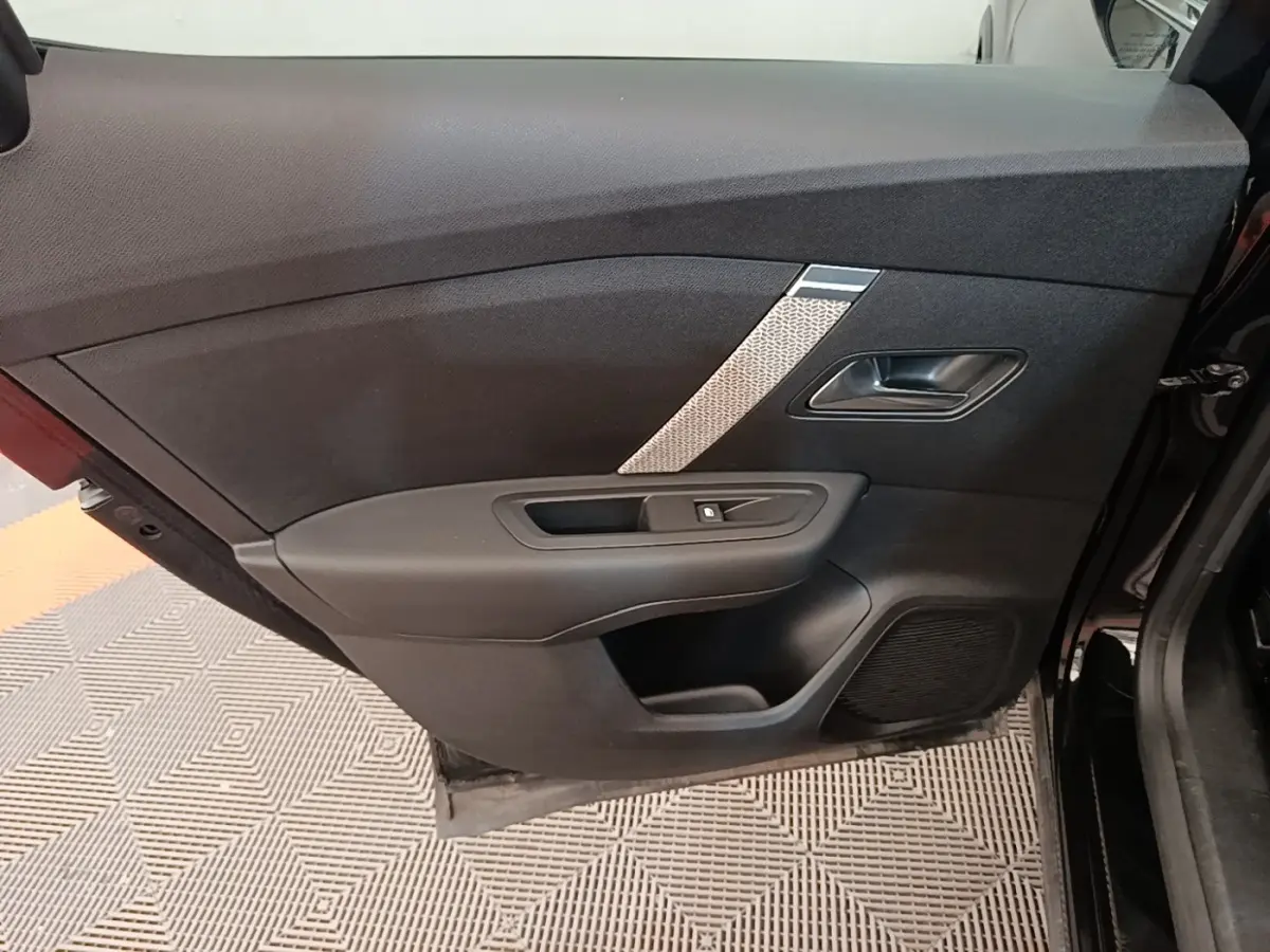 Vue intérieure de la porte avant gauche noire du Citroën C4 X 2023 avec insert décoratif gris et commande de vitre.