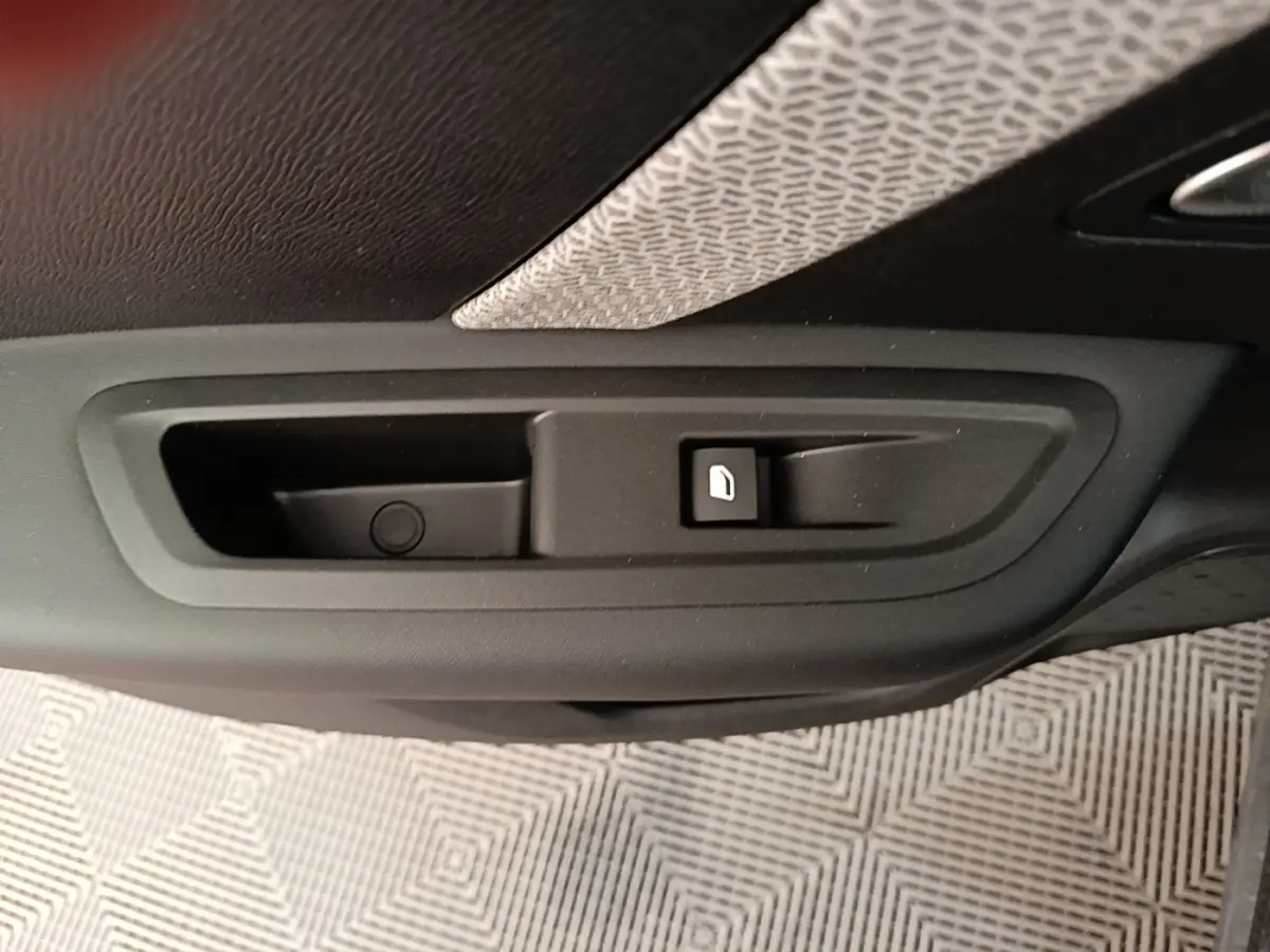 Gros plan sur la poignée intérieure de porte avec bouton de verrouillage, tissu gris et noir visible, intérieur Citroën C4 X.