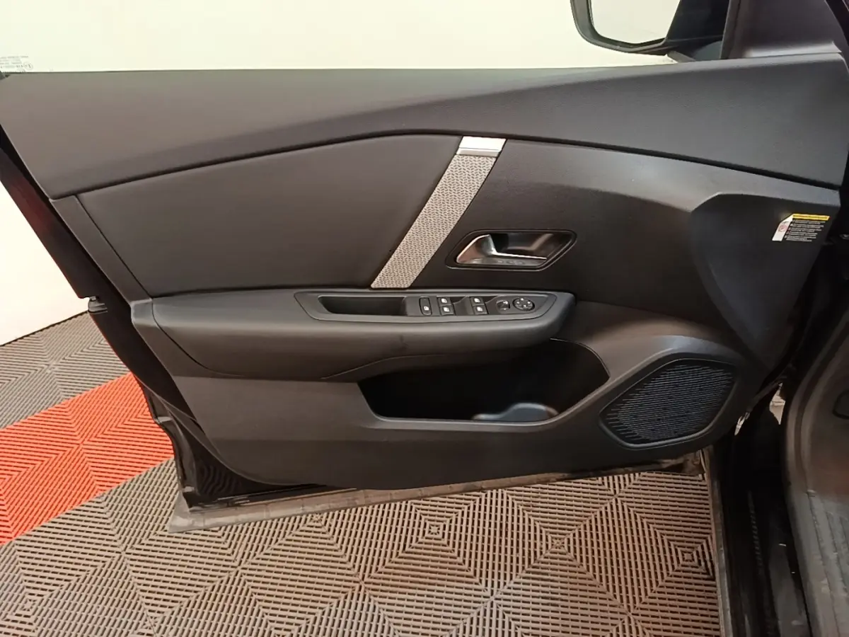 Vue intérieure de la porte avant gauche noire du Citroën C4 X 2023 avec commandes de vitres et haut-parleur intégré.
