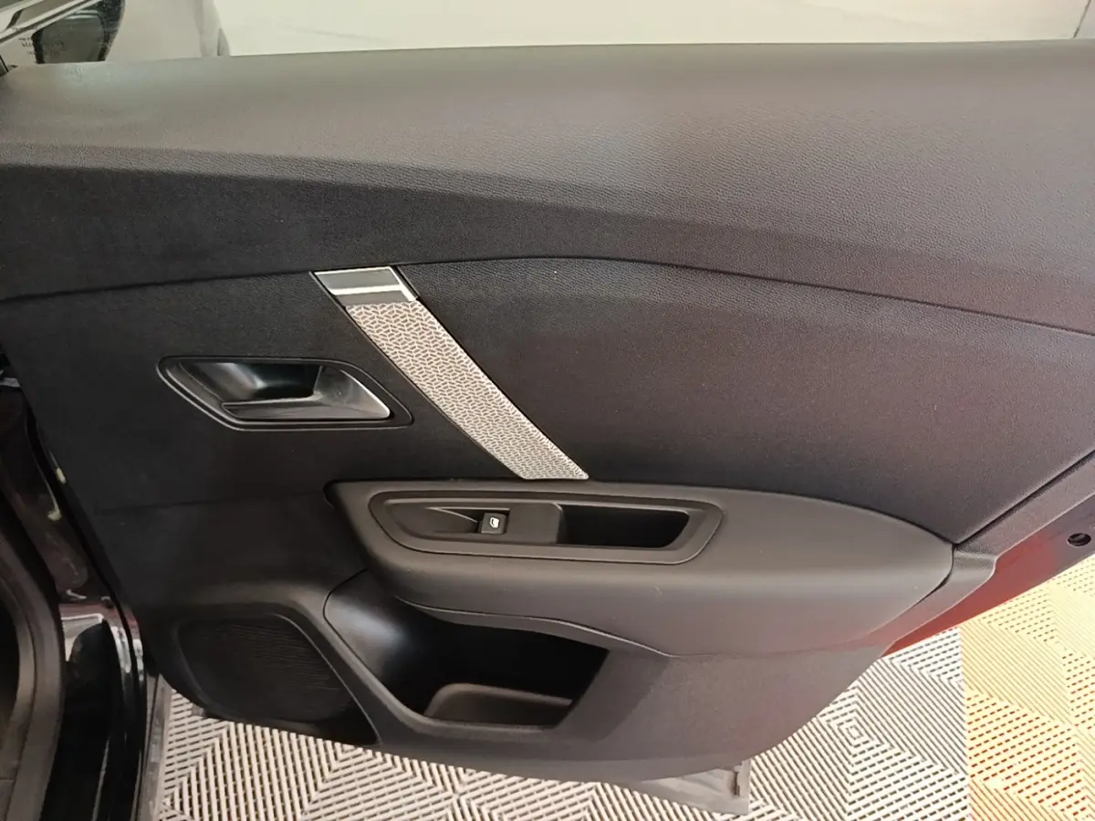 Vue intérieure de la porte côté gauche noire du Citroën C4 X 2023 avec insert décoratif gris et poignée intégrée.