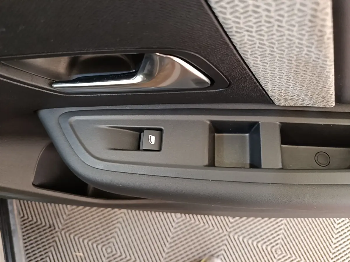 Gros plan sur la poignée intérieure et commande de vitre côté gauche d’une Citroën C4 X noire, finition 2023.
