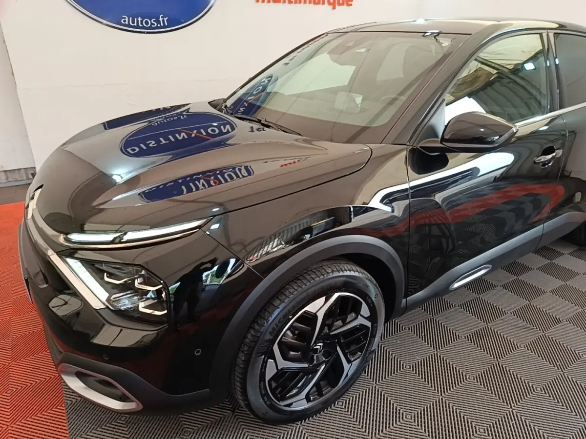 Vue 3/4 avant droit d'une Citroën C4 X noire brillante avec jantes noires et phares LED distinctifs.