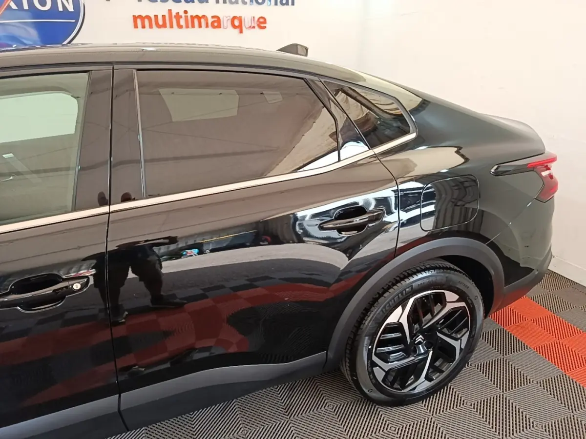 Vue côté droit arrière de la Citroën C4 X noire 2023, soulignant la ligne fluide et les jantes modernes.