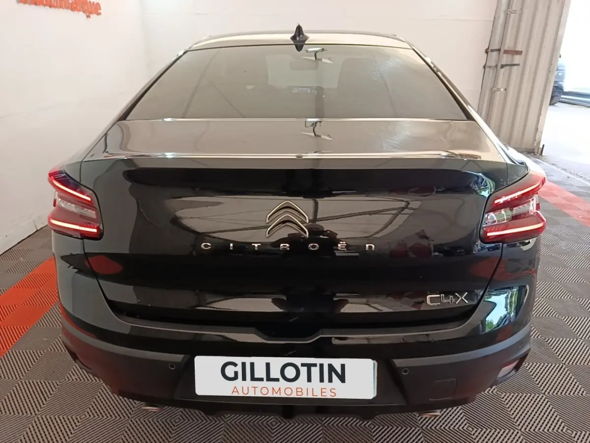 Vue arrière d'une Citroën C4 X noire 2023 avec feux LED allumés et logo distinctif sur coffre.