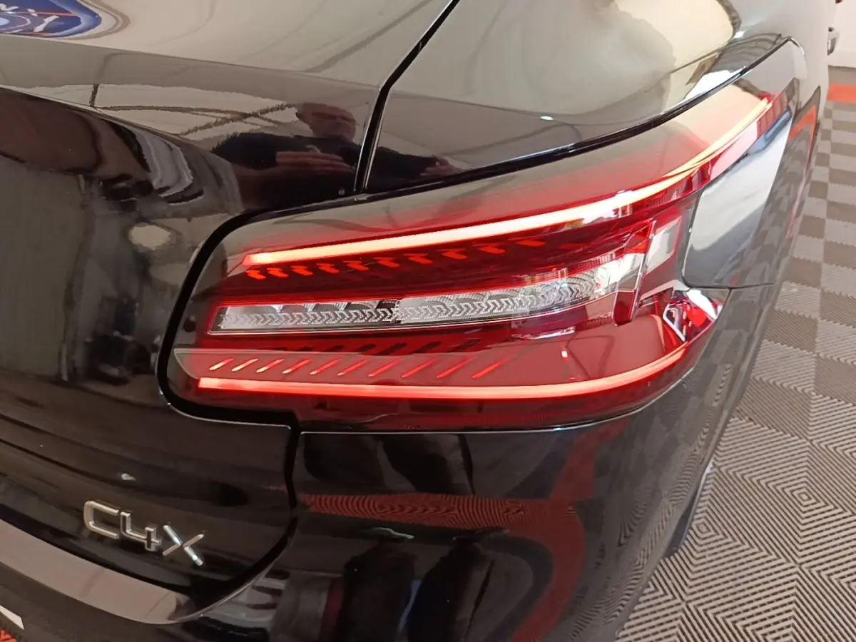 Feu arrière droit allumé et logo C4 X sur la partie arrière noire brillante du Citroën C4 X 2023.