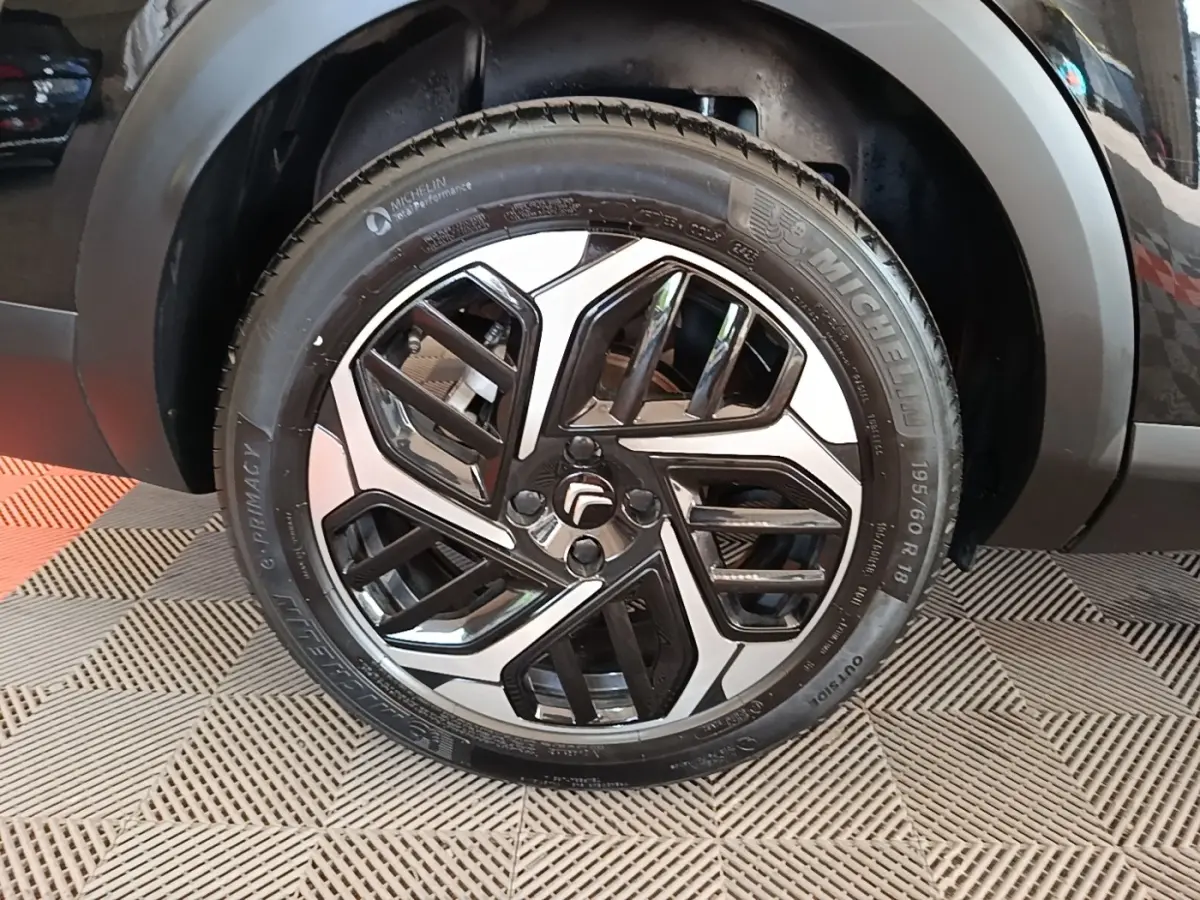 Gros plan sur la roue avant droite noire d'une Citroën C4 X 2023 avec jante alliage bicolore distinctive.