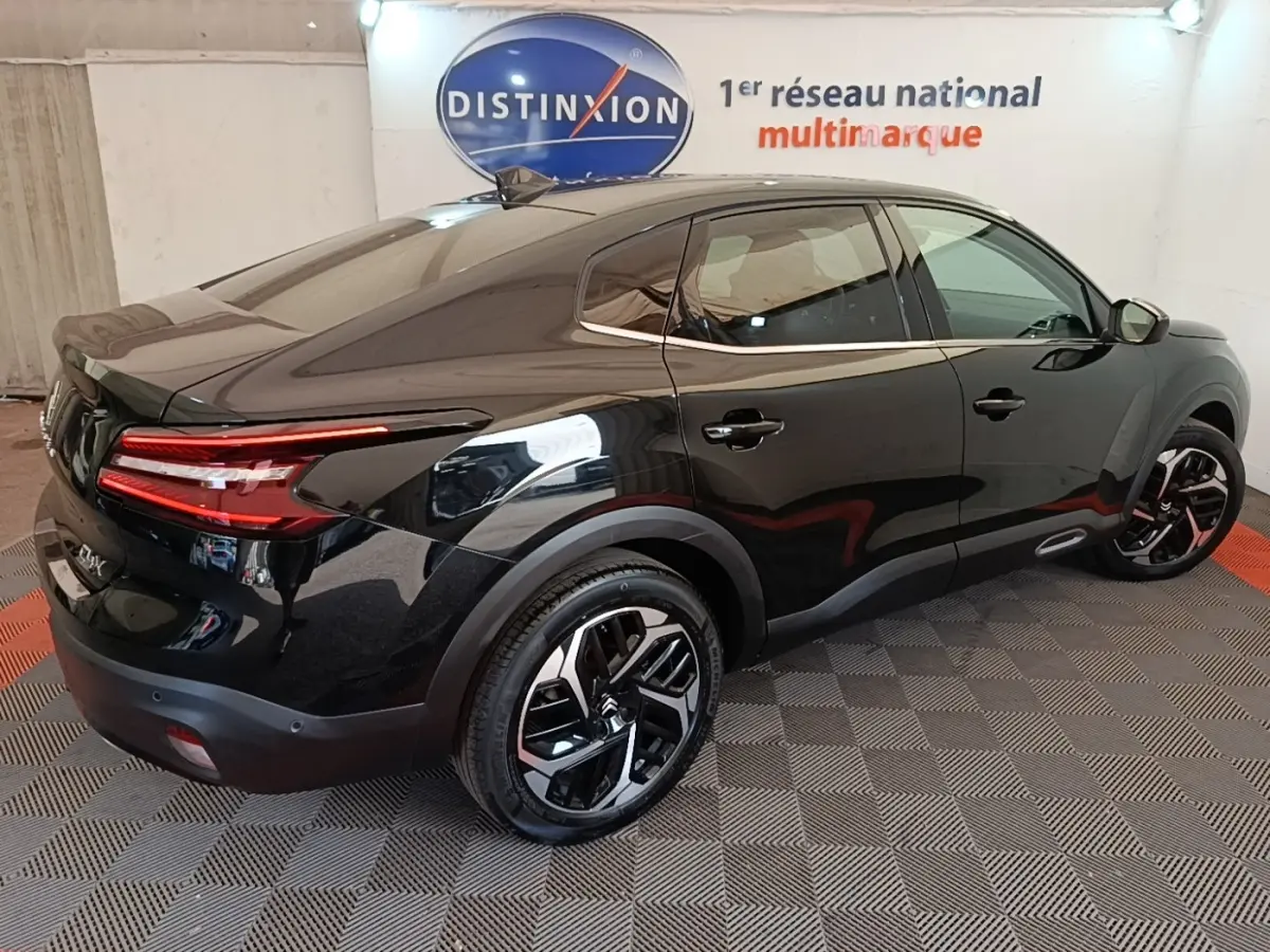 Vue 3/4 arrière droite d'une Citroën C4 X noire 2023 avec feux arrière LED et jantes noires distinctives.