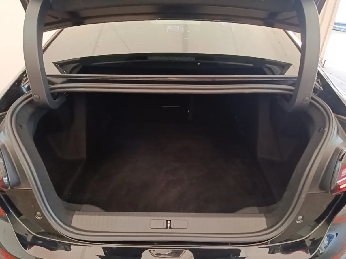 Coffre ouvert vu de l'arrière d'une Citroën C4 X noire 2023, espace de chargement spacieux et propre.