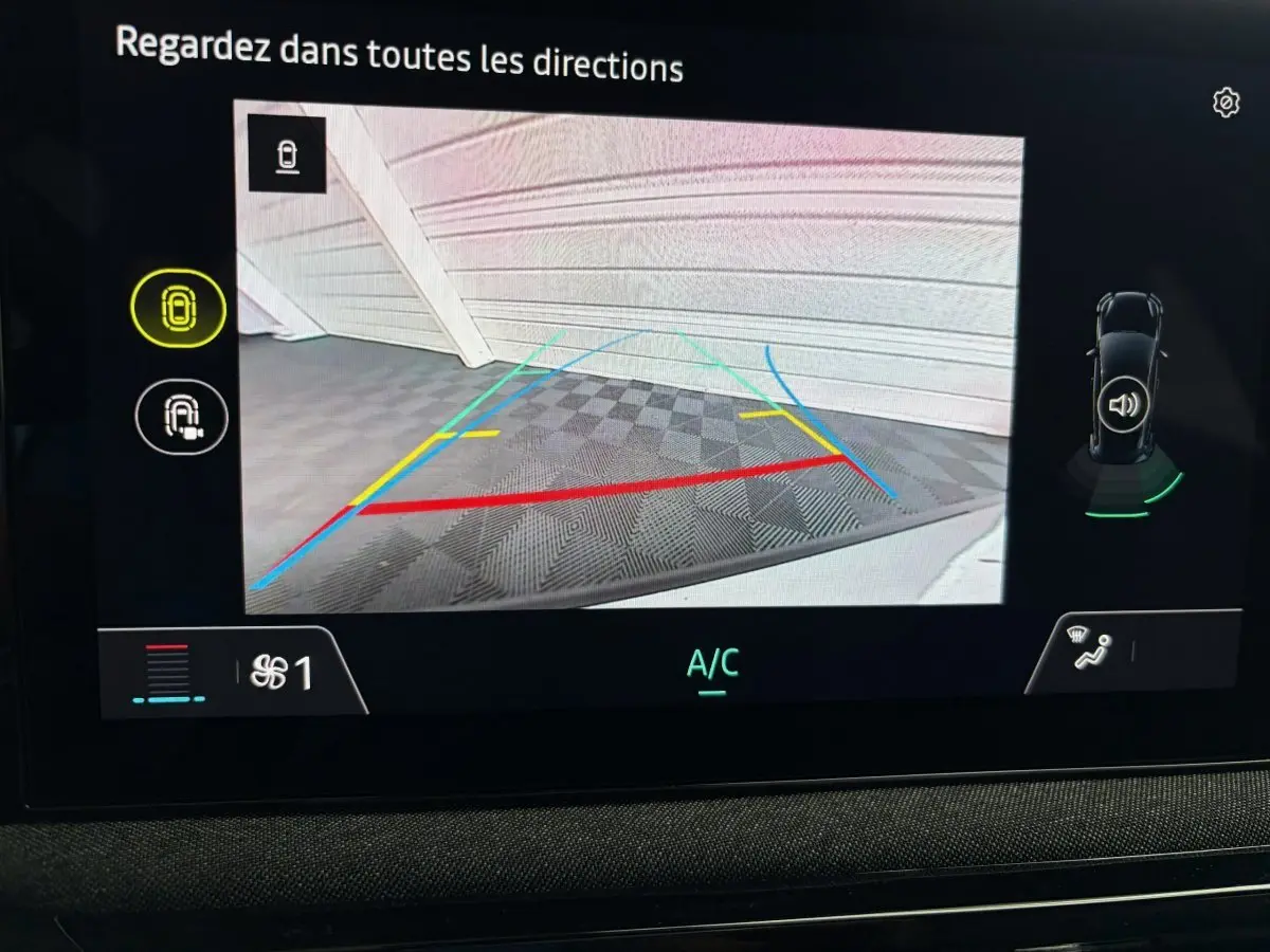 Affichage de la caméra de recul de la Renault Clio blanche 2026 avec lignes de guidage colorées et vue intérieure du tableau de bord.