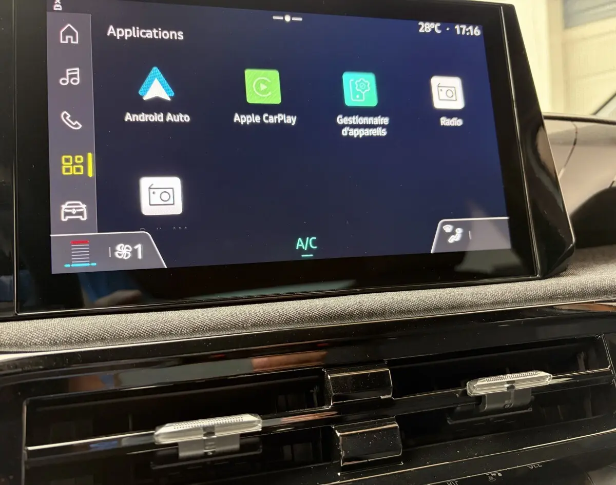 Écran tactile central de la Renault Clio blanche 2026 montrant les applications Android Auto et Apple CarPlay, vue intérieure frontale.