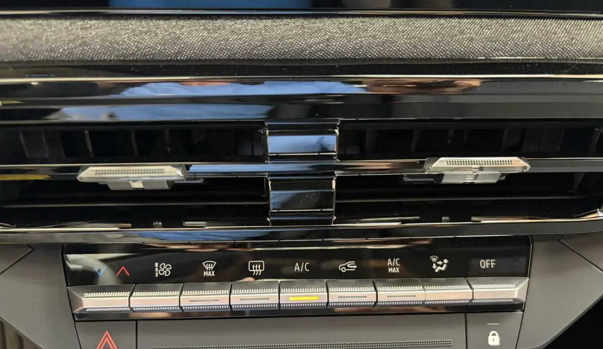 Détail de la console centrale noire de la Renault Clio 2026 blanche, montrant les commandes de climatisation et les aérateurs.