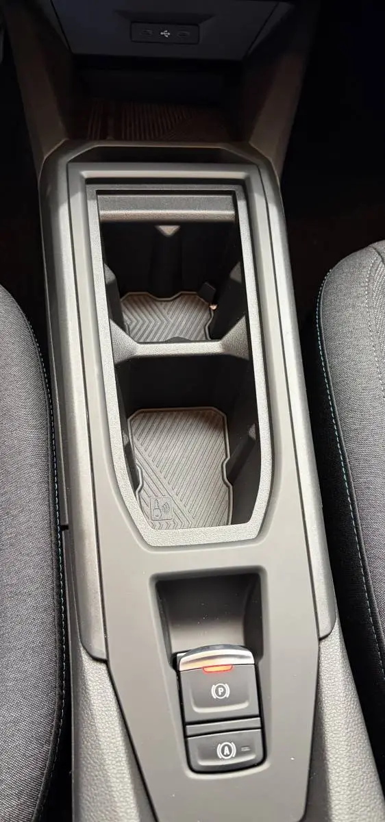Vue rapprochée de la console centrale noire de la Renault Clio 2026, avec porte-gobelets et commandes électroniques.