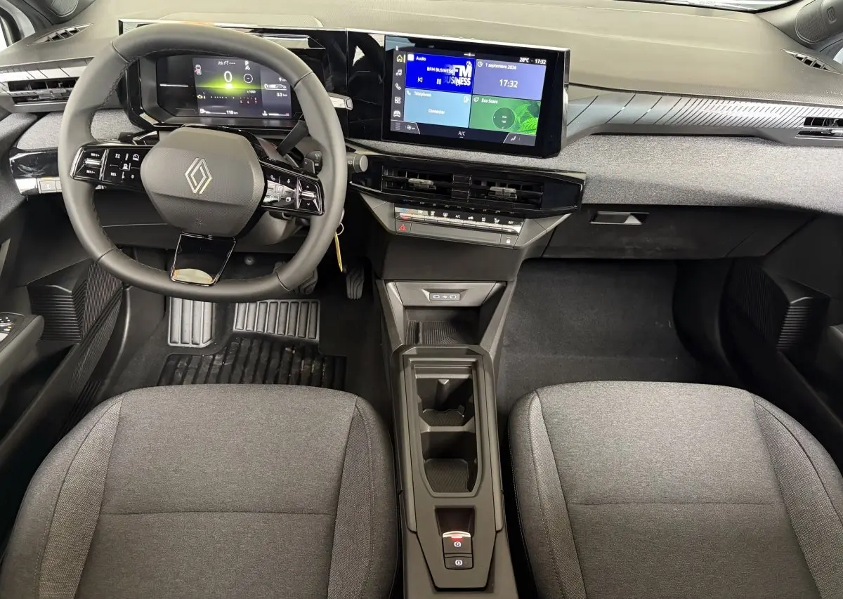 Vue intérieure frontale du tableau de bord de la Renault Clio blanche 2026 avec écran tactile et volant multifonction.