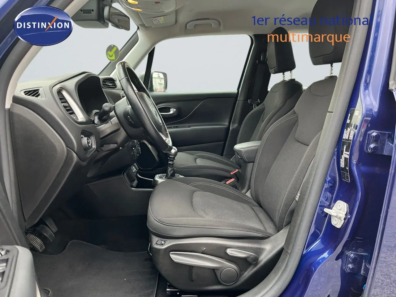 Intérieur côté conducteur du Jeep Renegade bleu 2020, montrant sièges noirs et tableau de bord avec boîte manuelle.