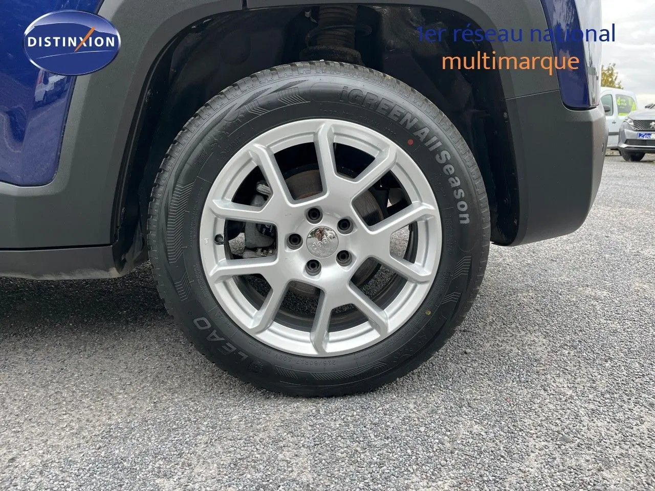 Gros plan sur la roue avant droite d’un Jeep Renegade bleu 2020 avec jante argentée et pneu toutes saisons.