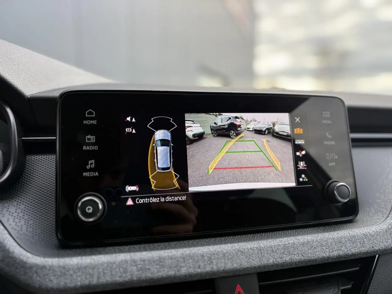 Écran central du Skoda Kamiq gris argent affichant la caméra de recul avec guidage de trajectoire en parking.