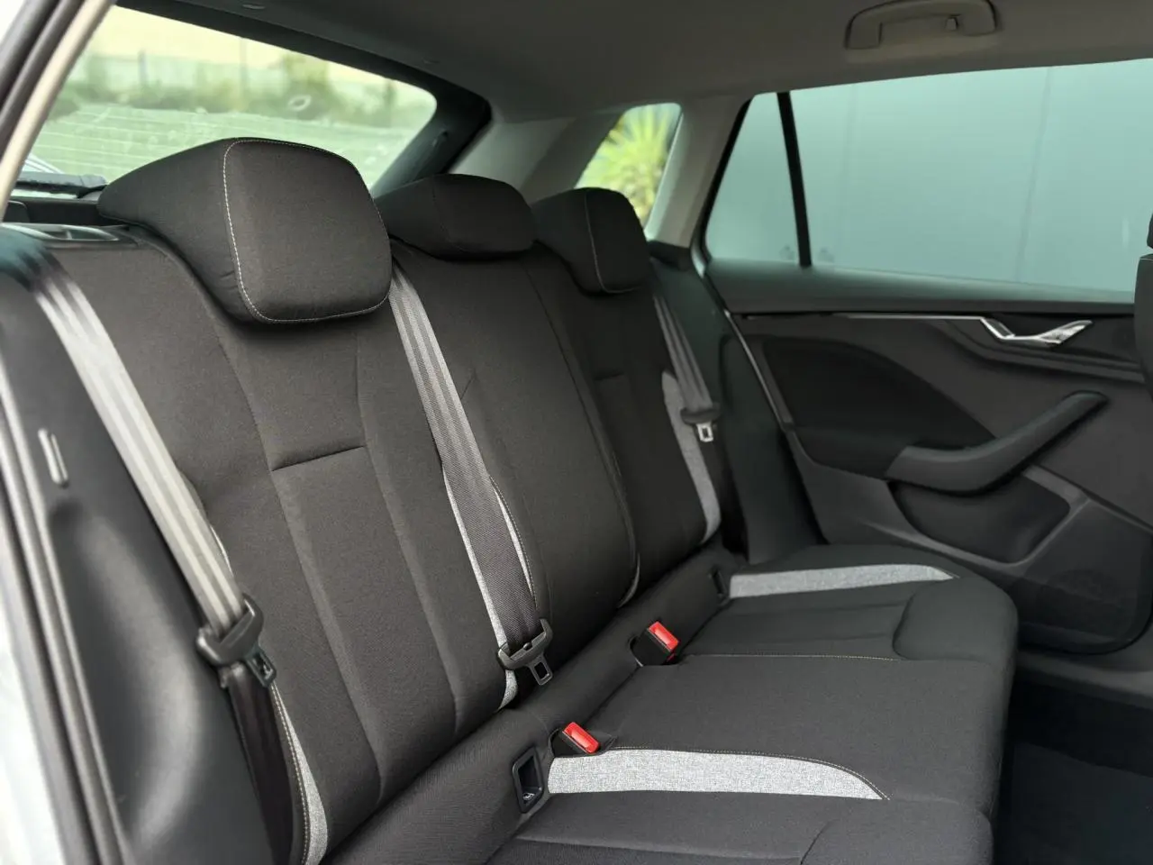 Vue latérale droite de la banquette arrière noire et grise du Skoda Kamiq TSI 116 DSG7 2025 avec ceintures visibles.