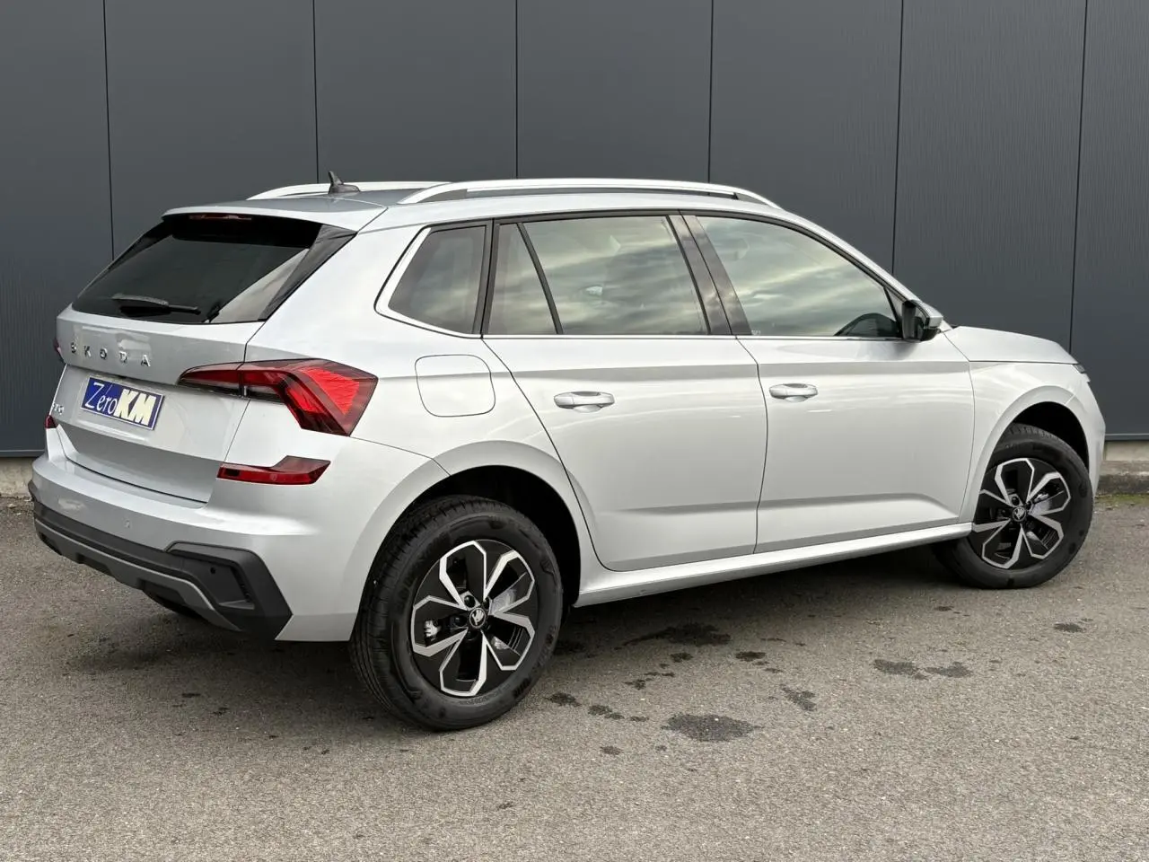 SKODA KAMIQ gris argent vu de trois quarts arrière droit avec vitres surteintées et jantes alliage noires.