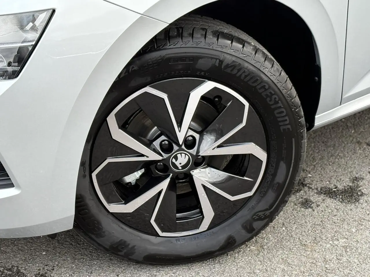 Gros plan sur la jante alliage noire et argentée du côté avant gauche d'une SKODA KAMIQ gris argent 2025.