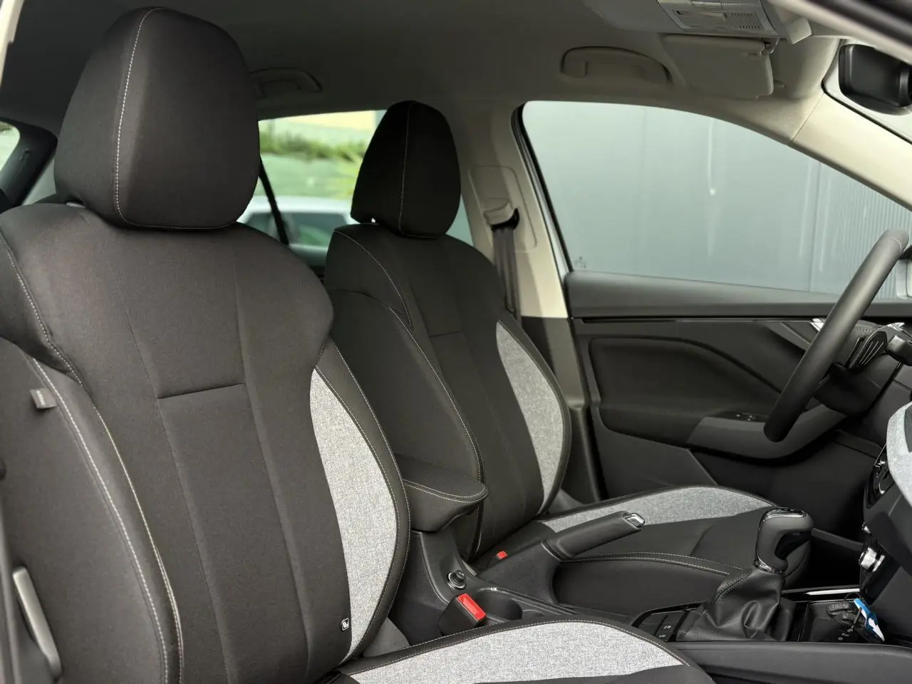 Vue intérieure côté conducteur du Skoda Kamiq 2025, sièges tissu bicolore noir et gris avec surpiqûres contrastées.