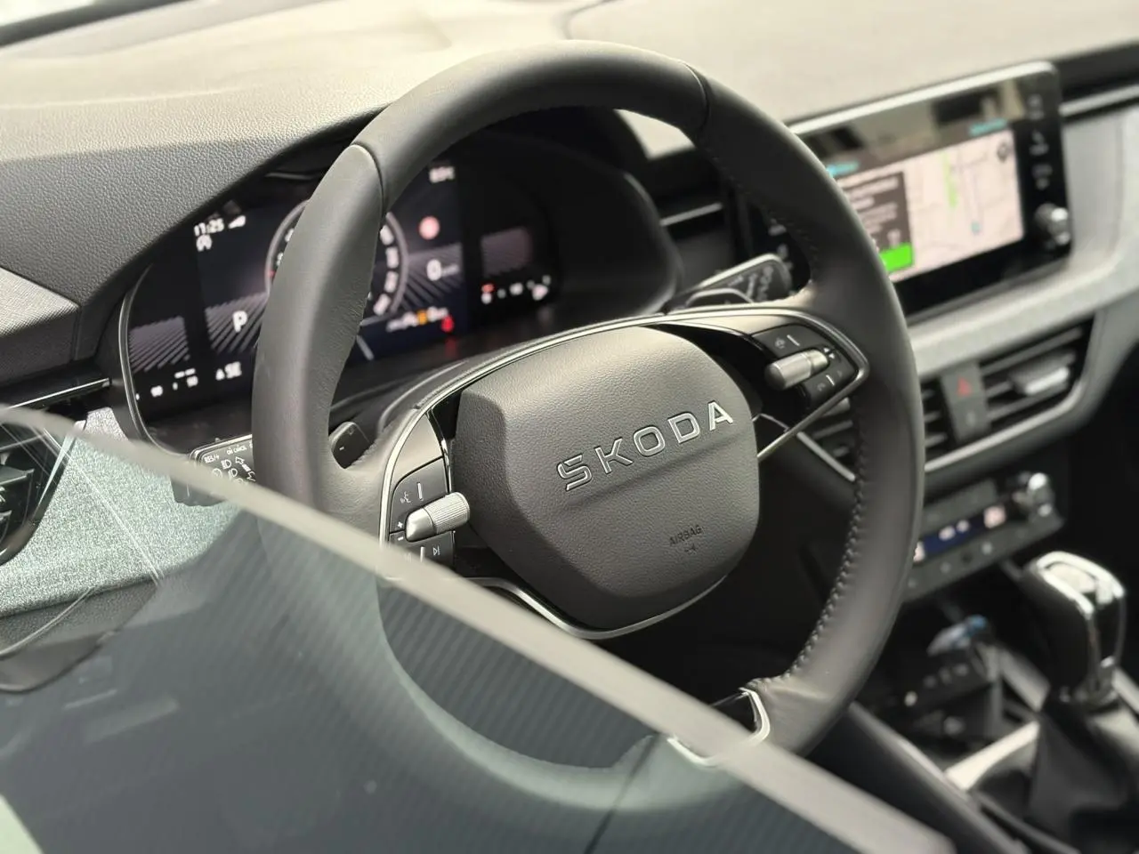 Vue intérieure rapprochée du volant cuir multifonctions SKODA du KAMIQ 2025 avec tableau de bord digital et écran tactile.