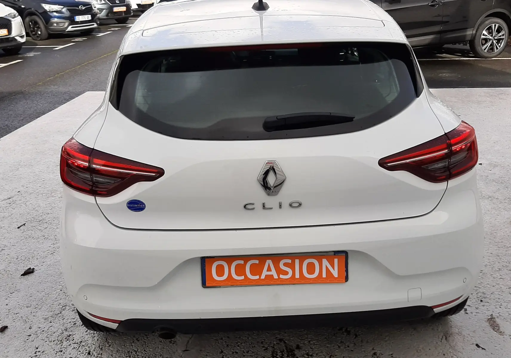 Vue arrière d'une Renault Clio V blanche de 2022 avec plaque "OCCASION" visible sur un parking extérieur.