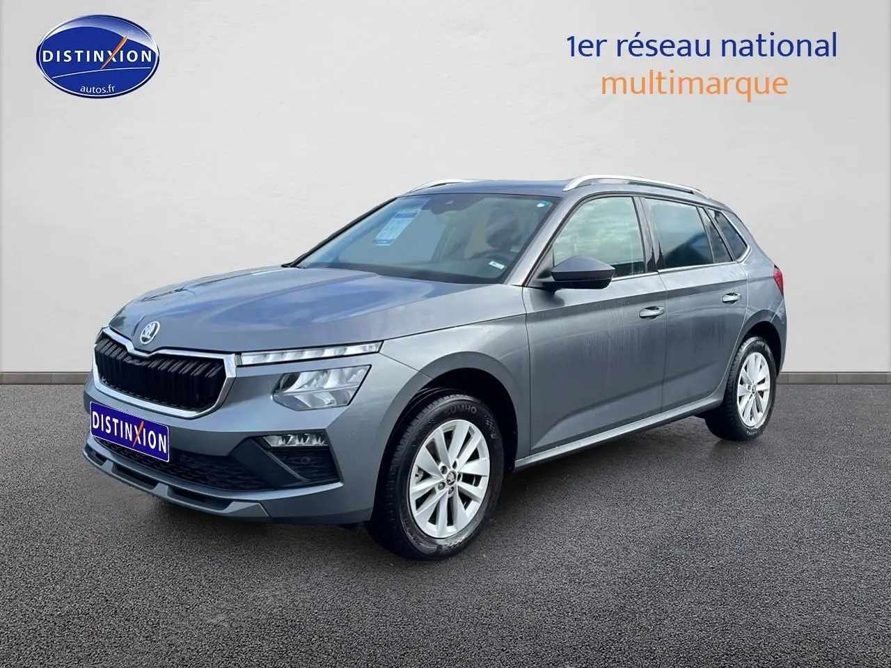 Vue 3/4 avant droit d'un Skoda Kamiq gris avec calandre chromée et jantes alu blanches.