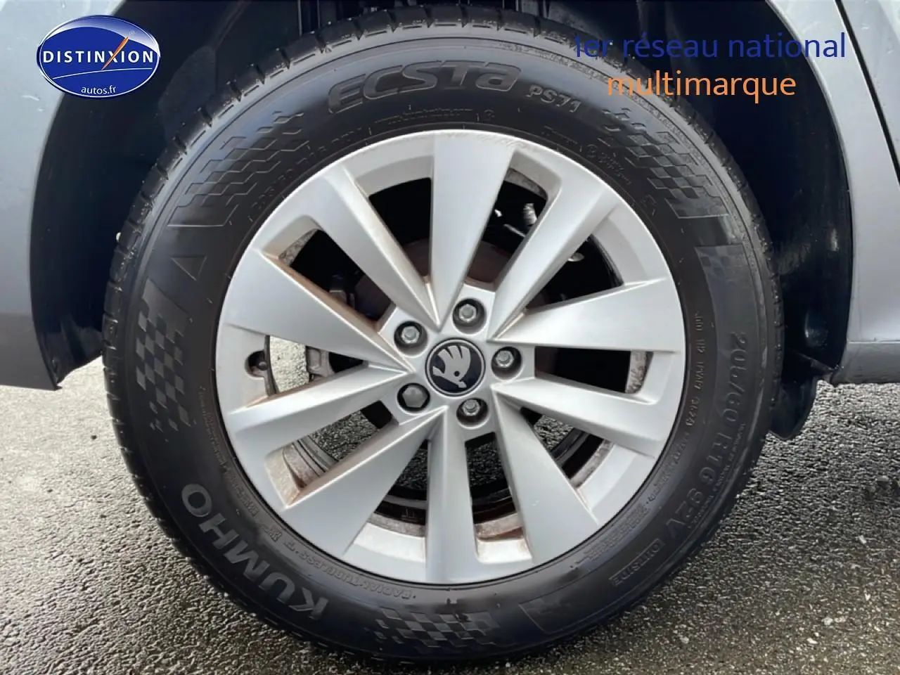 Gros plan sur la jante alu grise avec logo Skoda au centre, montée sur un pneu Kumho d’un Skoda Kamiq gris.