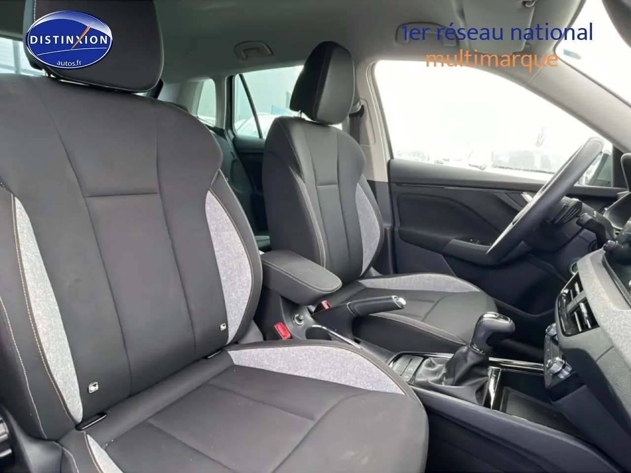 Vue intérieure côté droit du Skoda Kamiq 2025 gris, montrant les sièges avant avec accoudoir central et volant multifonction.