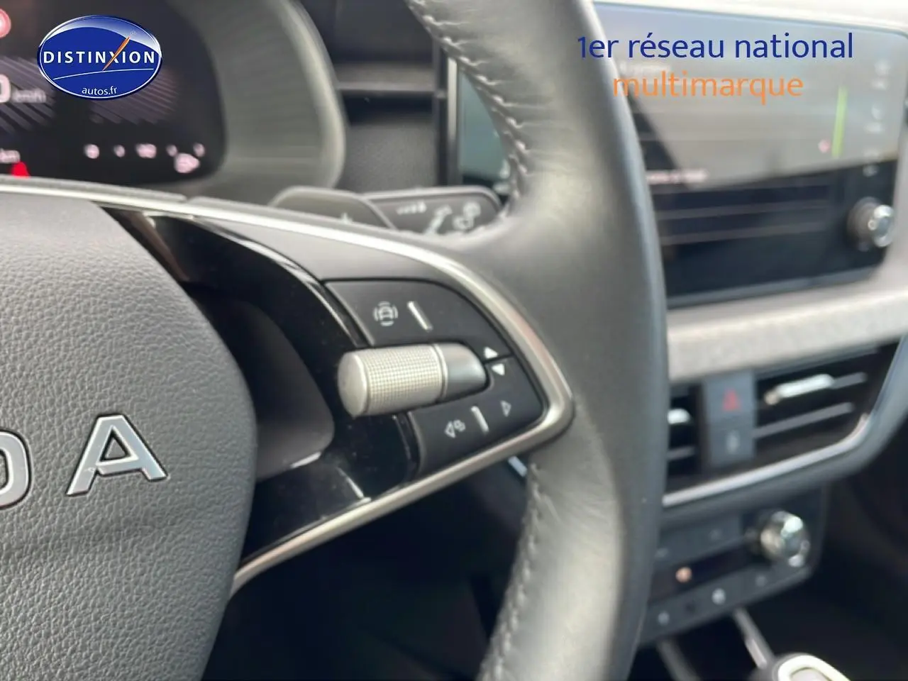 Gros plan sur le volant cuir multifonction gris du Skoda Kamiq 2025 avec commandes intégrées et tableau de bord flou.